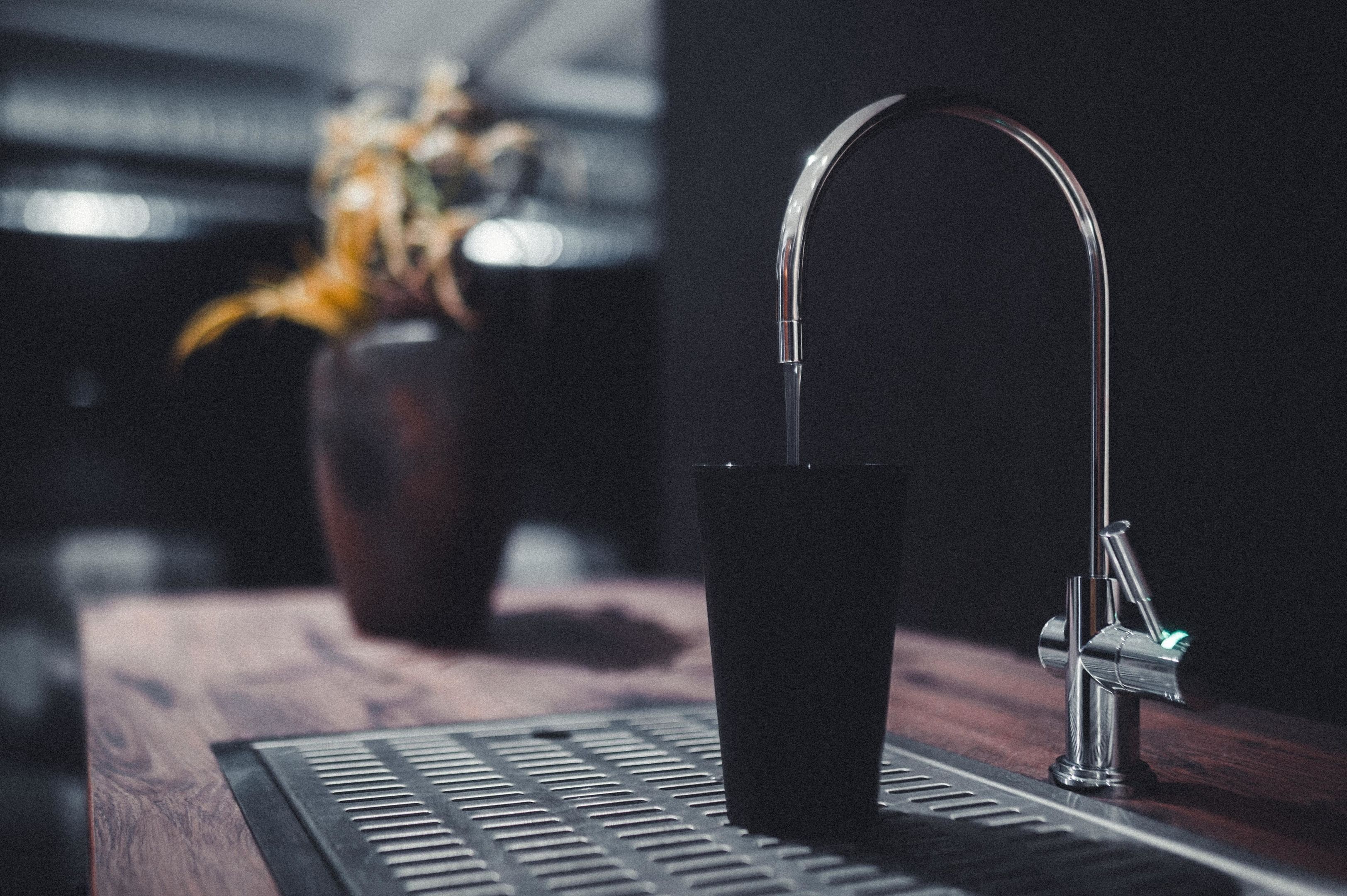 Una cocina moderna con un grifo de acero inoxidable, una taza oscura y una encimera de madera.
