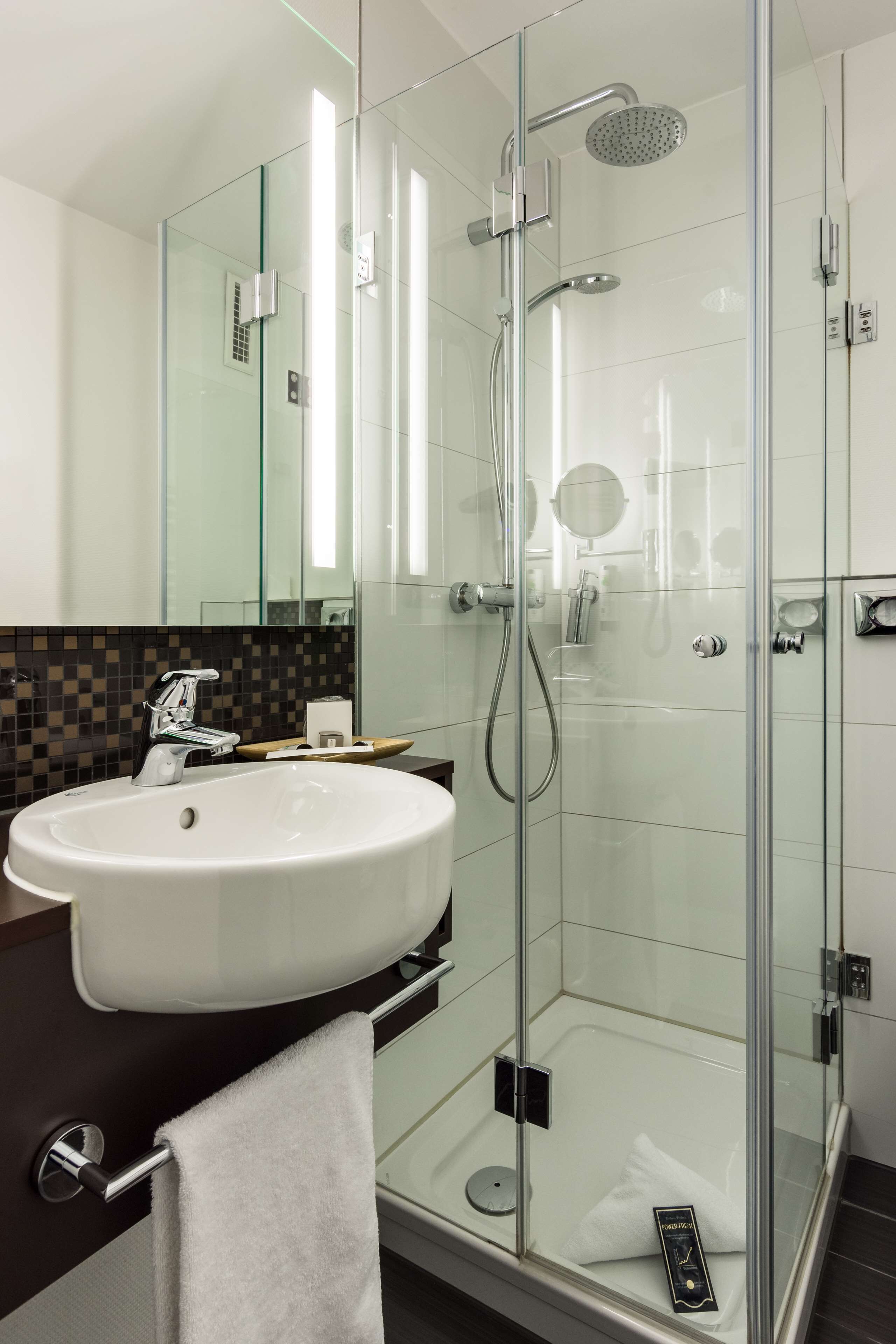A modern bathroom with a glass-enclosed shower, a white sink, and a mirror.