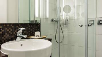 A modern bathroom with a glass-enclosed shower, a white sink, and a mirror.