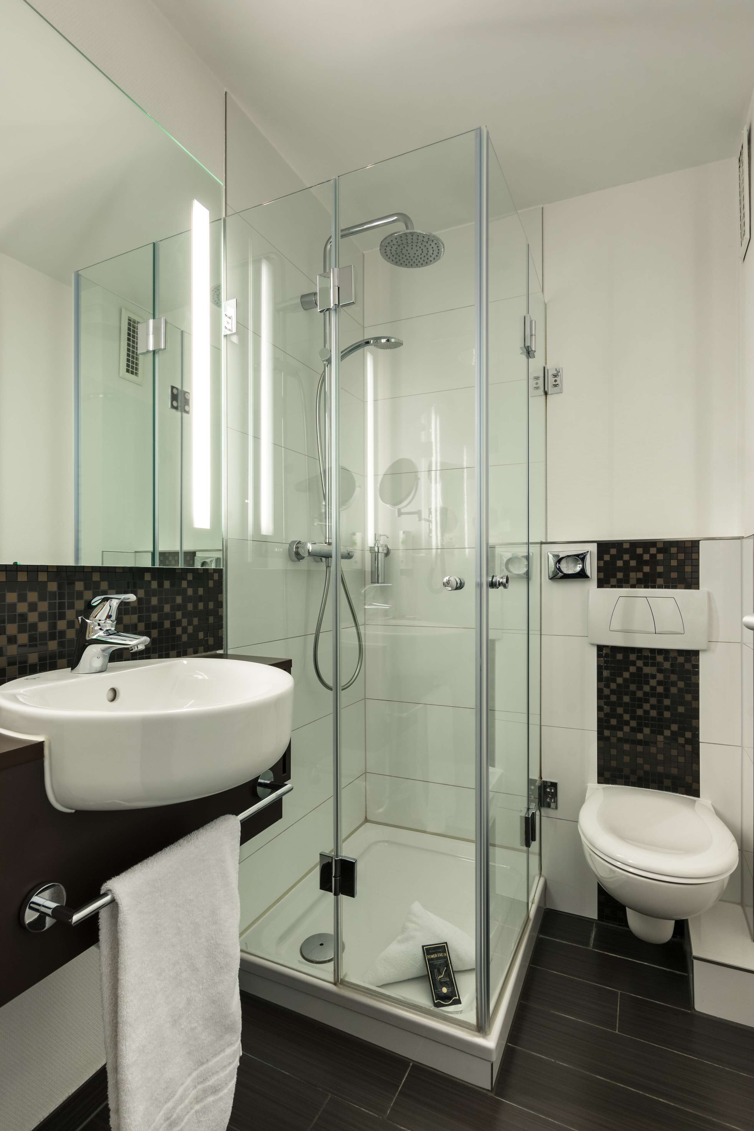 A modern bathroom with a glass-enclosed shower, a white sink, and a toilet.