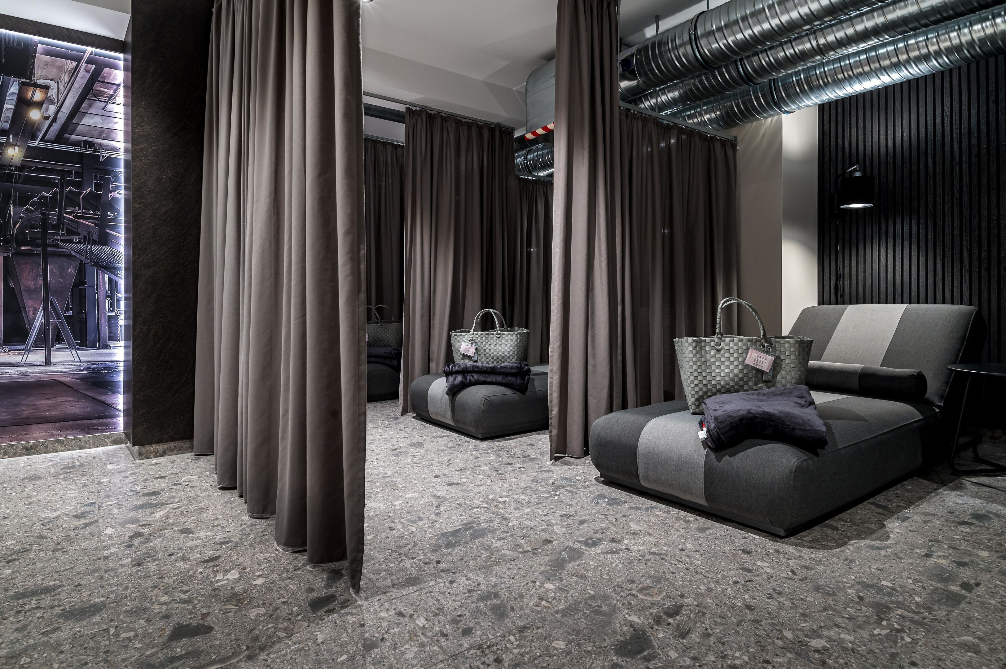 Een moderne hotelkamer met een bank, een stoel, een klein tafeltje en uitzicht buiten.