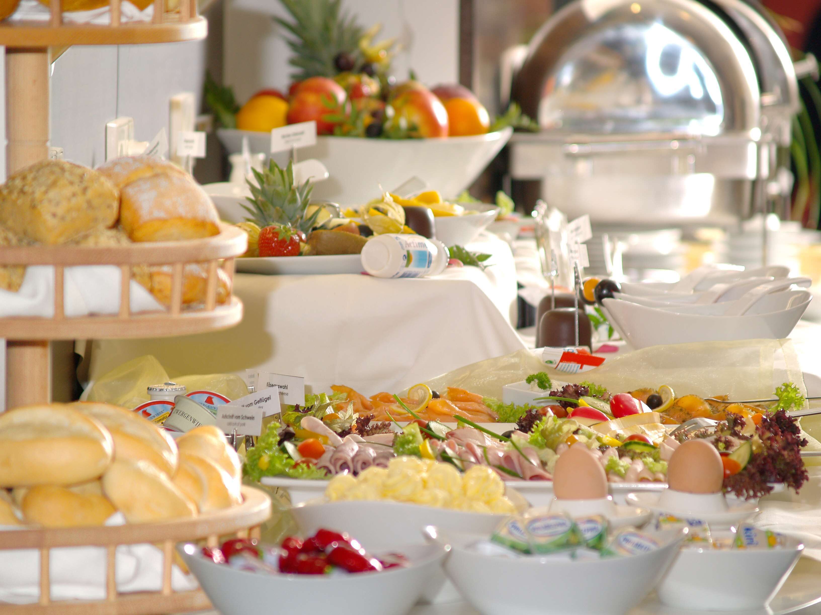 A buffet with various food items including bread, fruits, salads, and eggs.