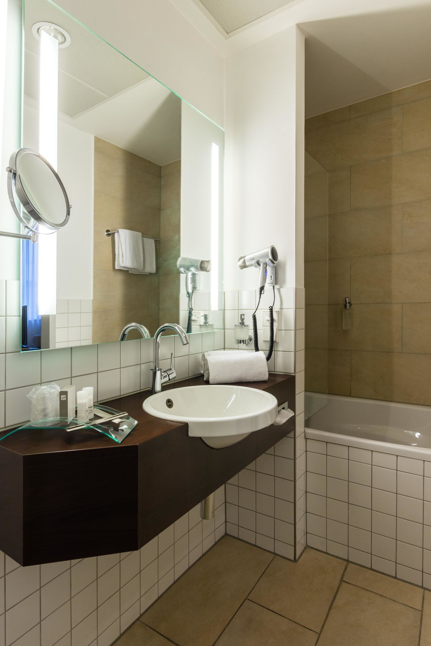 Un baño moderno con un espejo grande, un lavabo, un secador de pelo y una bañera.
