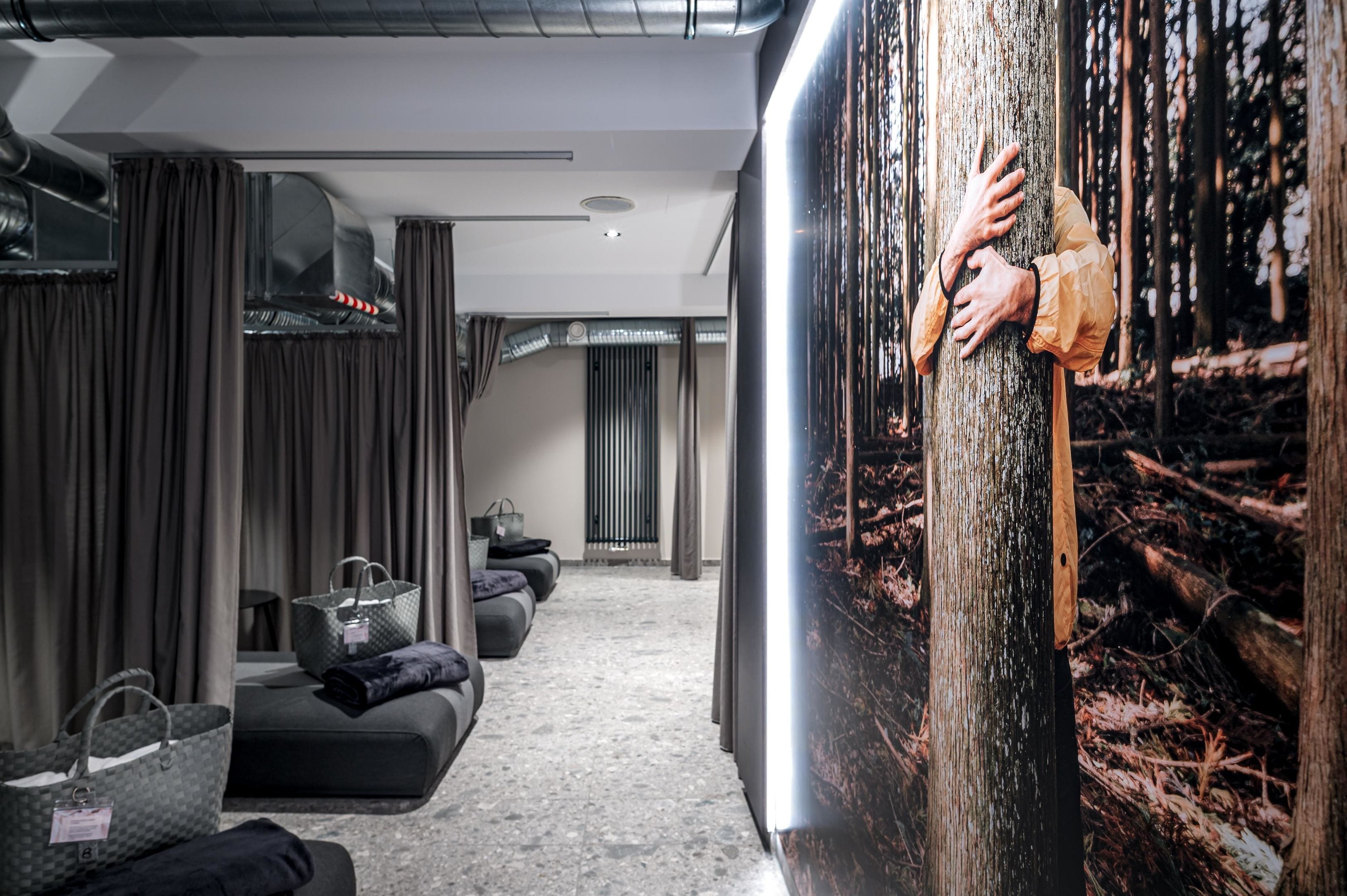 Ein modernes Hotelzimmer mit einem großen Fenster, einem Sofa, einem Sessel und einer Holztür.
