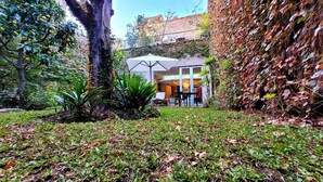 A modern house with a patio area, surrounded by lush greenery and a large tree. - 248 Finisterra Hotel Boutique Argentino (Buenos Aires)