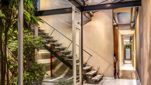 A modern interior with a glass staircase leading to a second floor, surrounded by indoor plants. - 248 Finisterra Hotel Boutique Argentino (Buenos Aires)