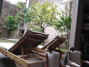 A room with two wooden lounge chairs and a large window overlooking a garden with trees and a wall. - 248 Finisterra Hotel Boutique Argentino (Buenos Aires)