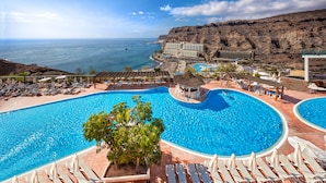 A resort with a large swimming pool, lounge chairs, and a view of the ocean. - Hotel Mogan Princess & Beach Club- All Inclusive (Mogan)