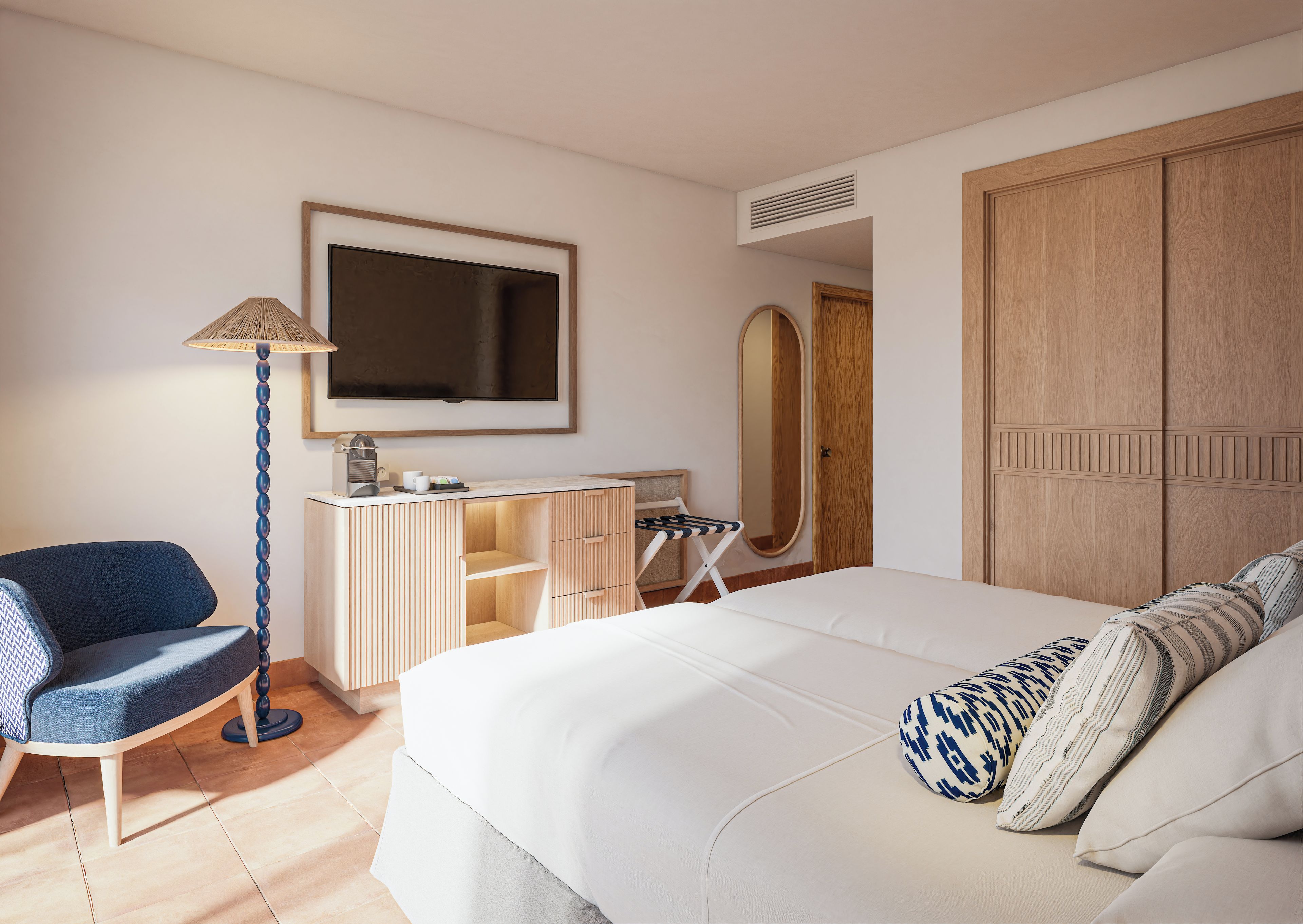 Quarto de hotel com uma cama, uma escrivaninha com cadeira, televisão e guarda-roupa.