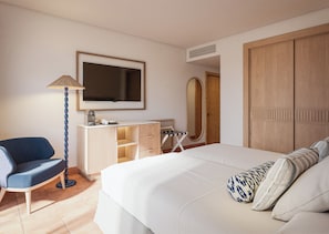 A hotel room with a bed, a desk with a chair, a television, and a wardrobe. -  Princess Mogán & Beach Club All Inclusive (Mogan)