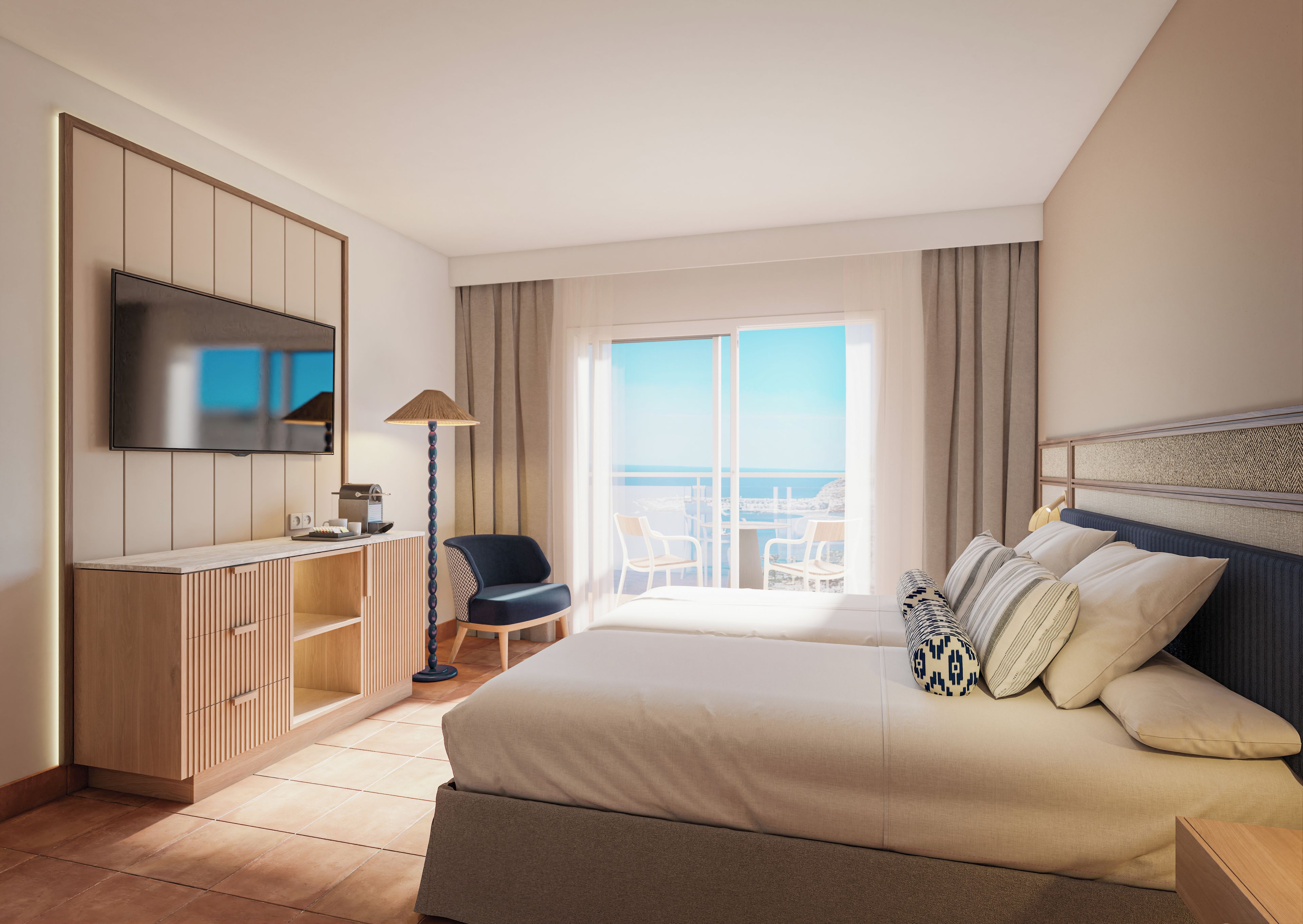 A hotel room with a bed, a TV, a desk, a chair, and a view of the sea.