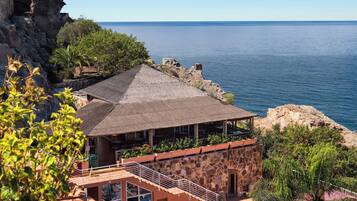 Un edificio costero con fachada de piedra, techo de paja y vista al mar.