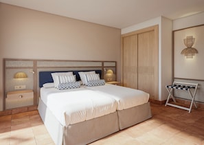 A bedroom with a large bed, a wardrobe, a bedside table, and a wall-mounted lamp. -  Princess Mogán & Beach Club All Inclusive (Mogan)