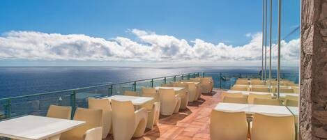 Une terrasse avec des tables et des chaises donnant sur la mer.