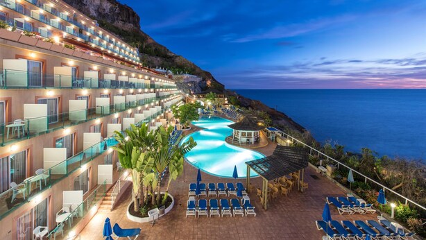 Un hôtel doté de nombreux balcons, d’une piscine et offrant une vue sur l’océan.