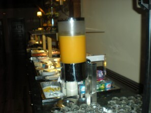 Zona de bar con un objeto alto y cilíndrico, posiblemente un coctelero, y un escurreplatos con varios vasos.