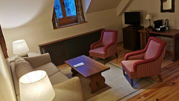 Un salón acogedor con un sofá, dos sillones, una mesa de centro, un televisor y una mesita con una lámpara.