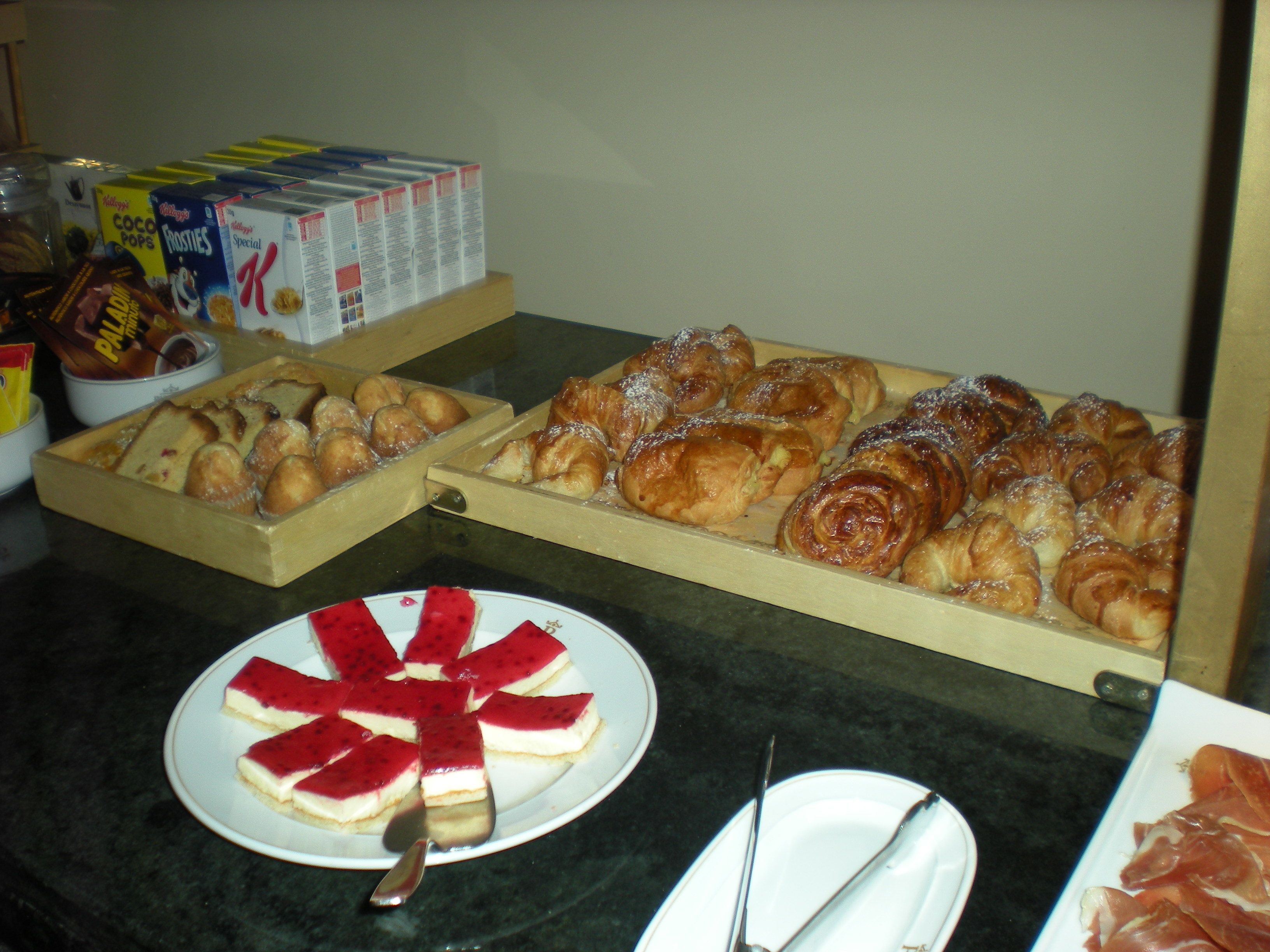 Ein Frühstücksbuffet mit verschiedenen Backwaren, einer Fruchtplatte und Müslischachteln.