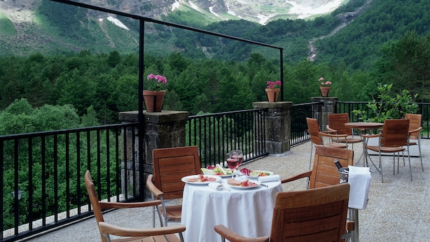 Una terraza con mesas y sillas con vistas a un paisaje montañoso.