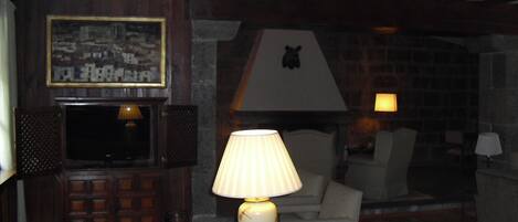 A cozy living room with a fireplace, a television, and a lamp.