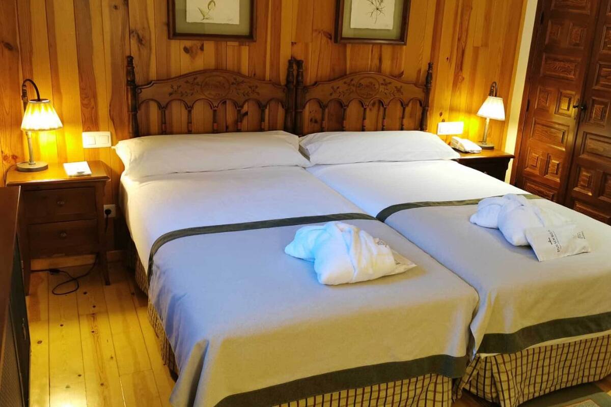 A double bed with a wooden headboard, two bedside tables with lamps, and a wooden wardrobe.