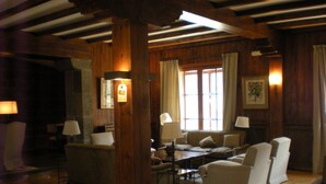 Un cuarto acogedor con vigas de madera, un sofá, sillones y una mesa.