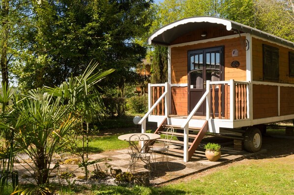 A wooden cabin with a porch, a table, and chairs, surrounded by greenery. - Auberge La Tomette, The Originals Relais (Vitrac)