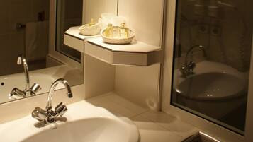 A bathroom with a white sink, a mirror, and a bathtub. There are wicker baskets on the sink counter.
