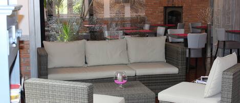 A cozy outdoor seating area with wicker furniture and a brick wall backdrop.