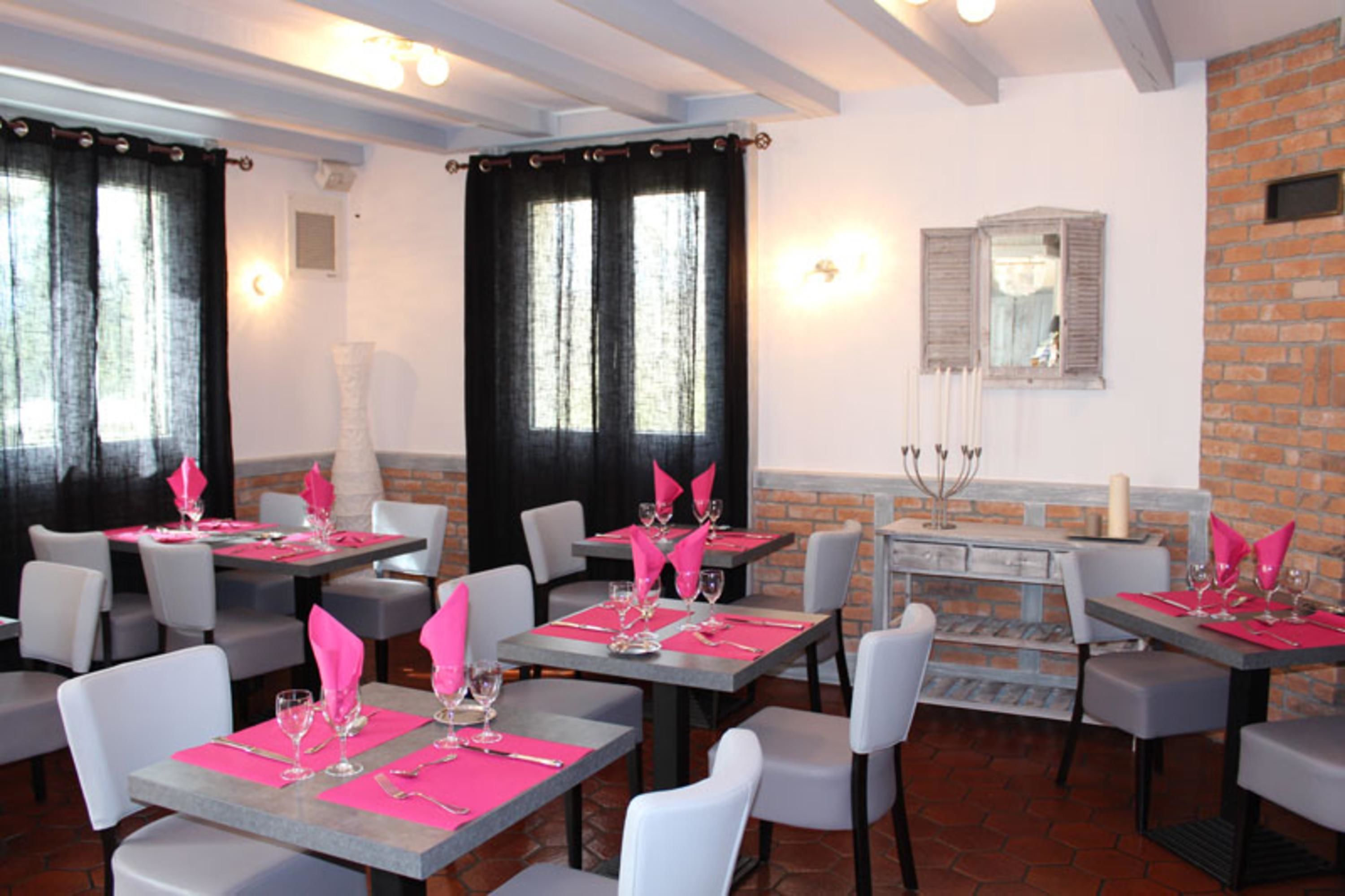 Un restaurant avec des tables dressées pour le service, doté d’un mur en briques et d’un miroir.