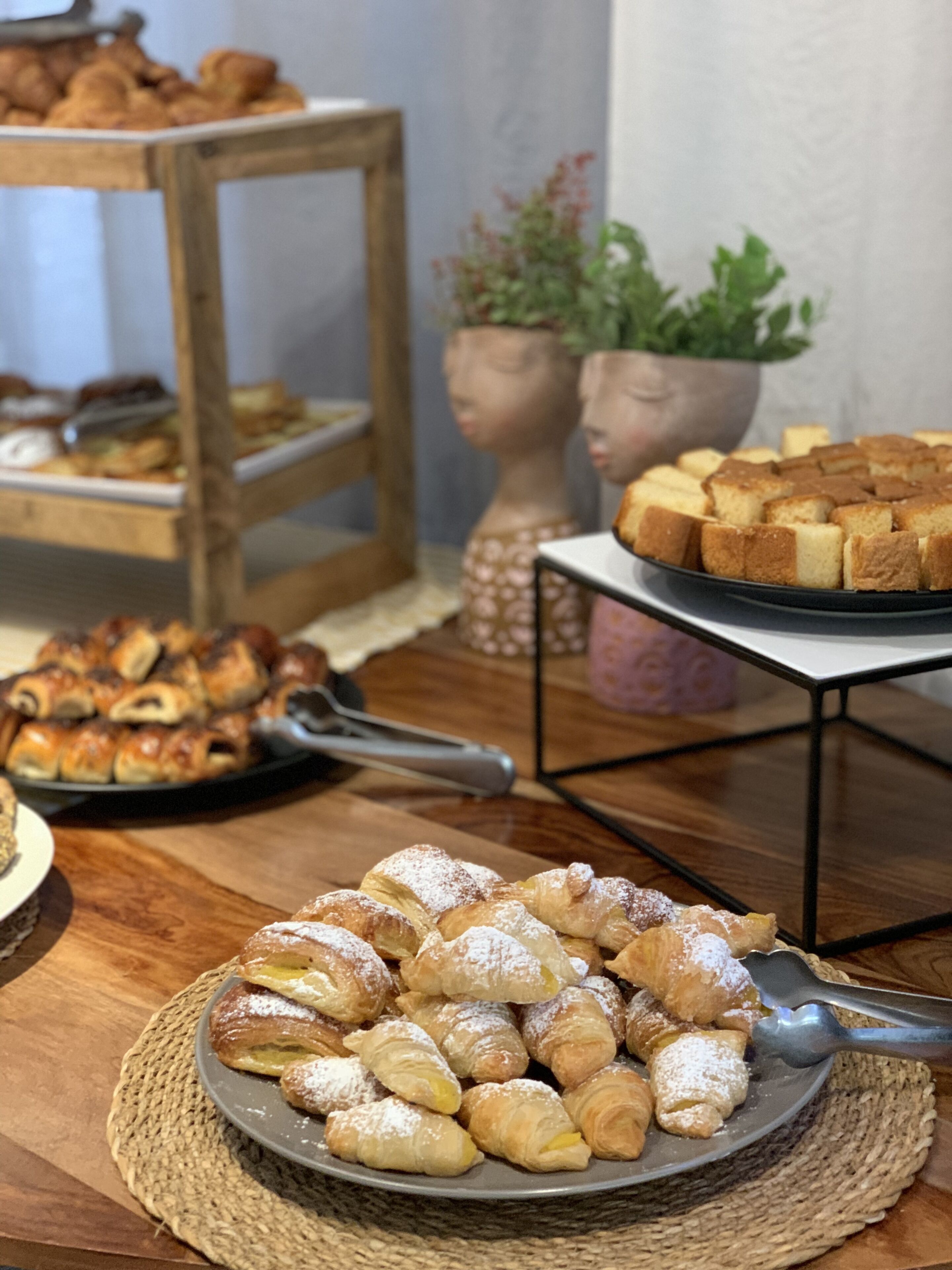 Variedad de productos de repostería a la vista, incluyendo croissants y pan, dispuestos sobre mesas y un mostrador.
