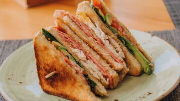 Un sandwich coupé en quatre morceaux, présenté sur une assiette en céramique.