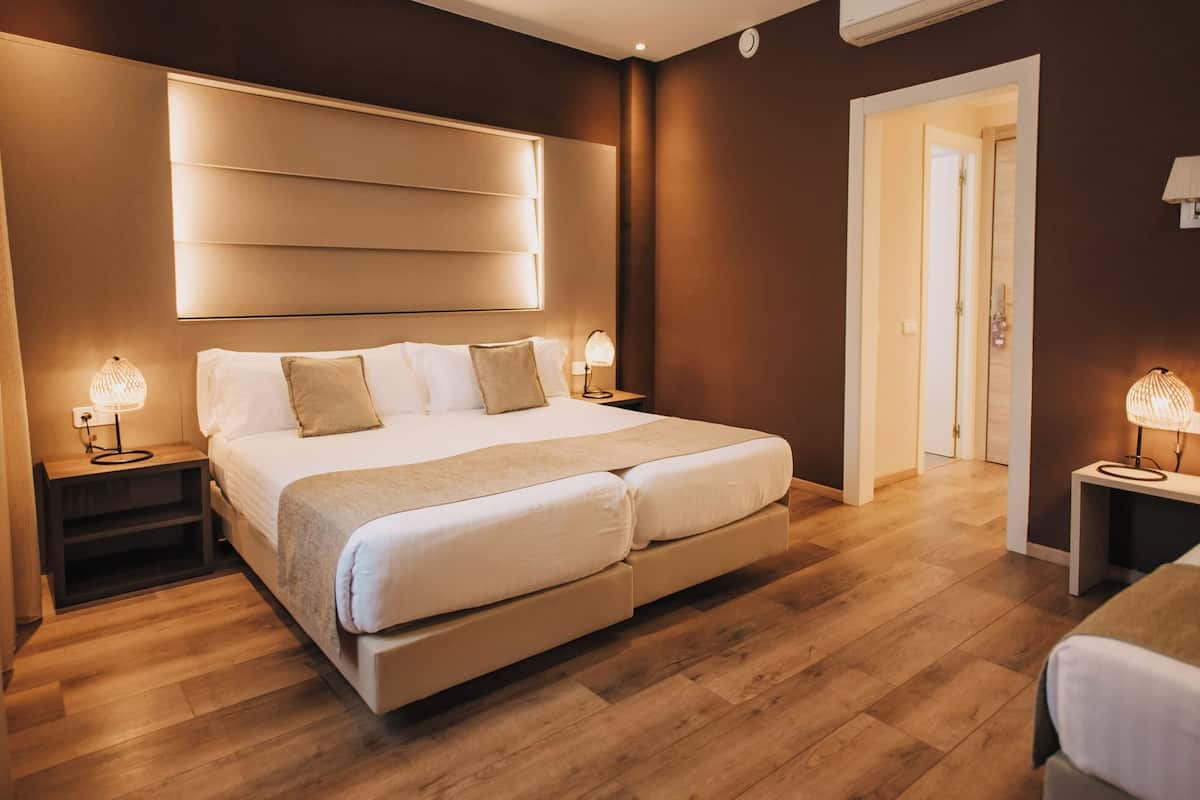 Un dormitorio moderno con una cama grande, lámparas de noche y suelo de madera.