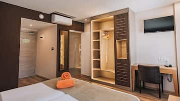 Una habitación de hotel con cama, escritorio, silla, televisor y armario.
