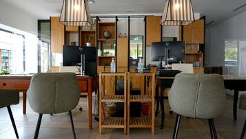 A modern office space with two desks, chairs, and a central shelving unit.