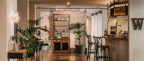 A modern kitchen with wooden flooring, a central island, bar stools, and a hanging light fixture.