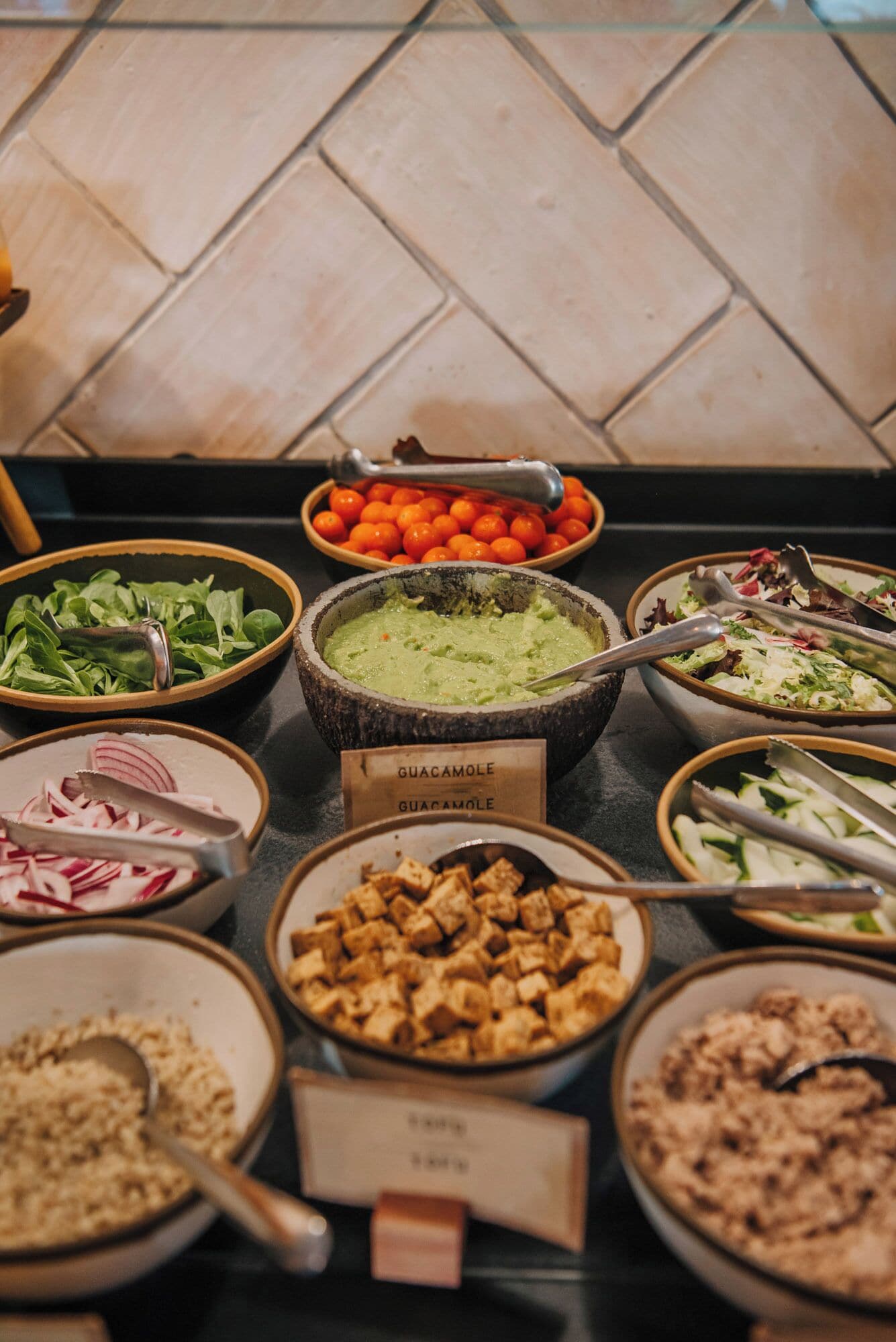 A buffet with various dishes including guacamole, salads, and other food items.