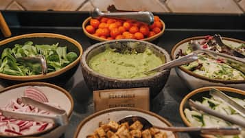 Un buffet proposant divers plats, notamment du guacamole, des salades et d’autres mets.