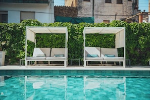 A poolside area with two white lounge chairs under a canopy, surrounded by lush green foliage. - Hotel Windsor Tossa – Adults Only +16 (Tossa de Mar)
