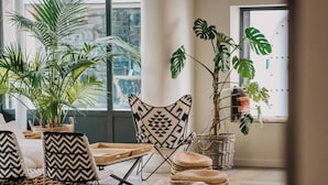 Una sala de estar moderna con un ventanal grande, una zona de comedor con mesa y sillas, y varias plantas en macetas.