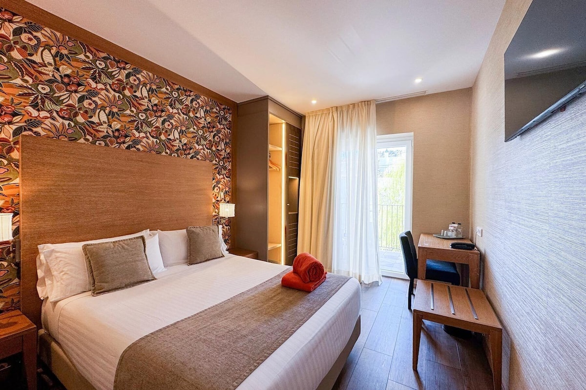 Habitación de hotel con una cama grande, un escritorio y vistas al exterior.