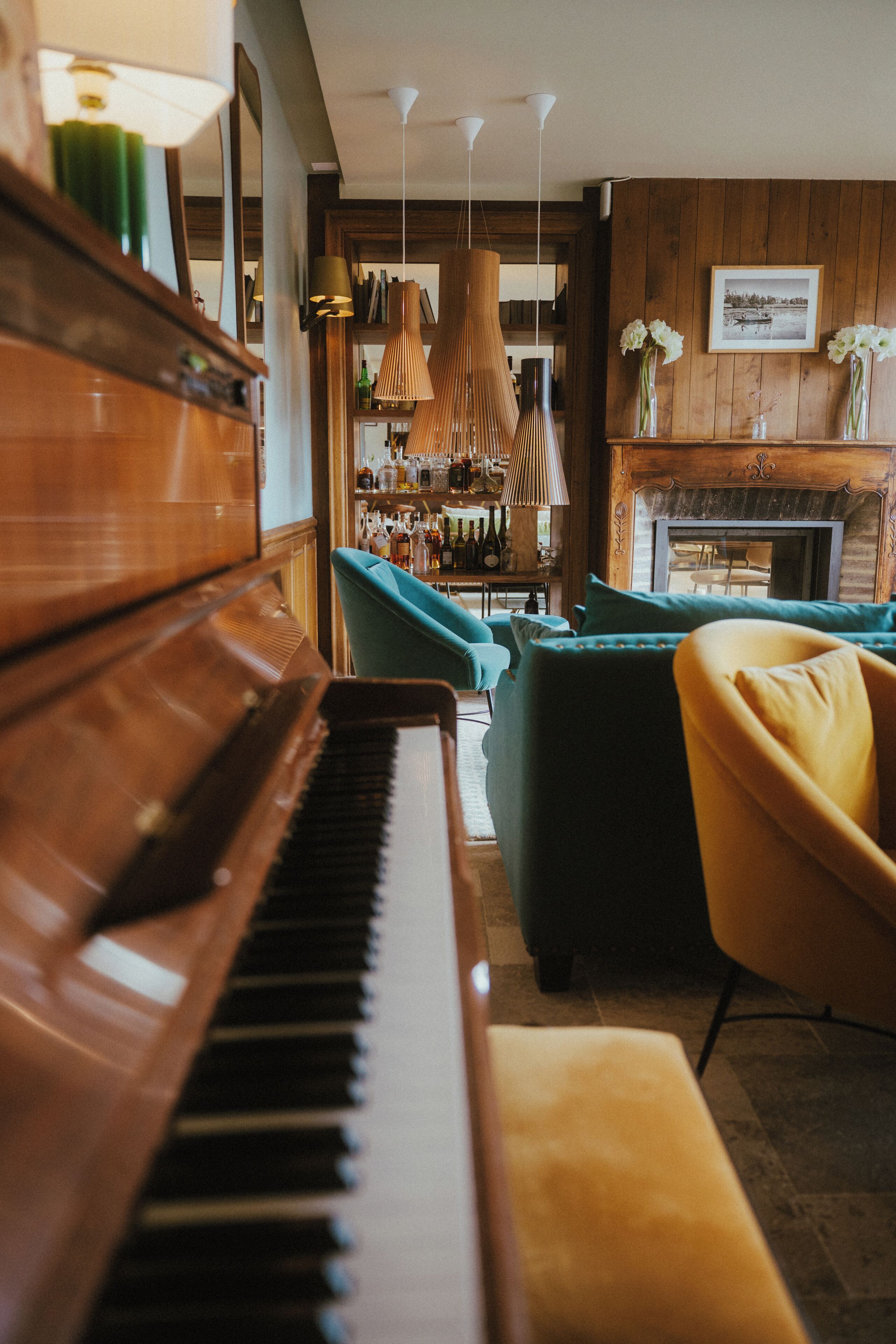 Un piano, butaques color turquesa, una zona de bar amb ampolles i una llar de foc.