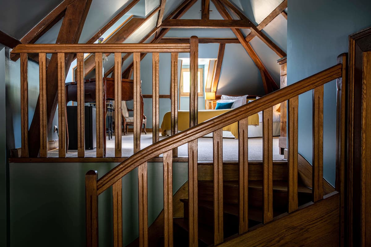 A wooden staircase with a view of a bedroom.