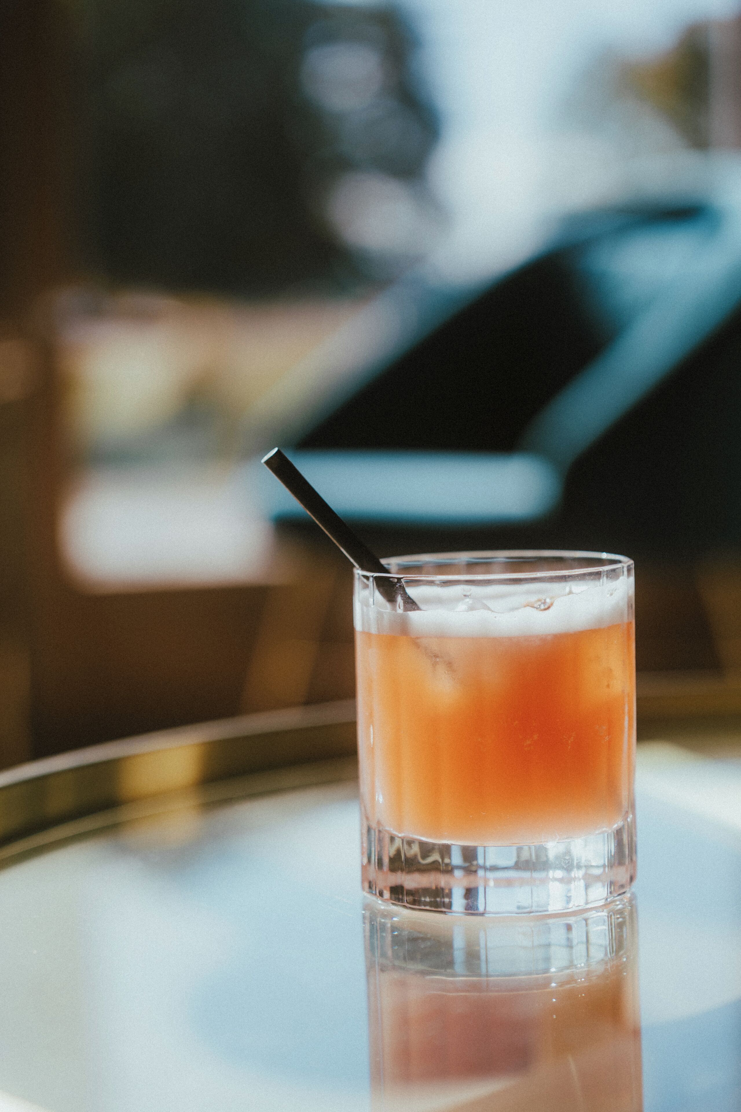 A glass with a straw on a reflective surface.