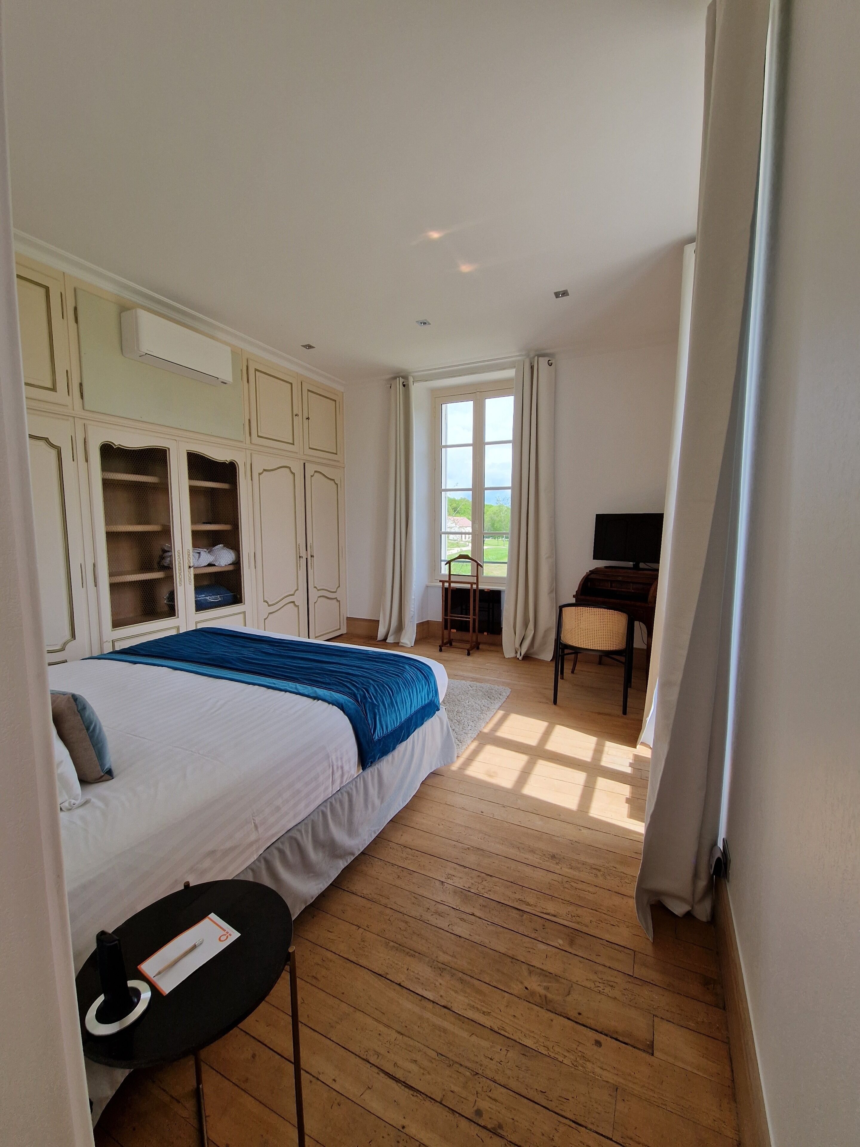 A bedroom with a bed, a desk, a chair, and a TV.