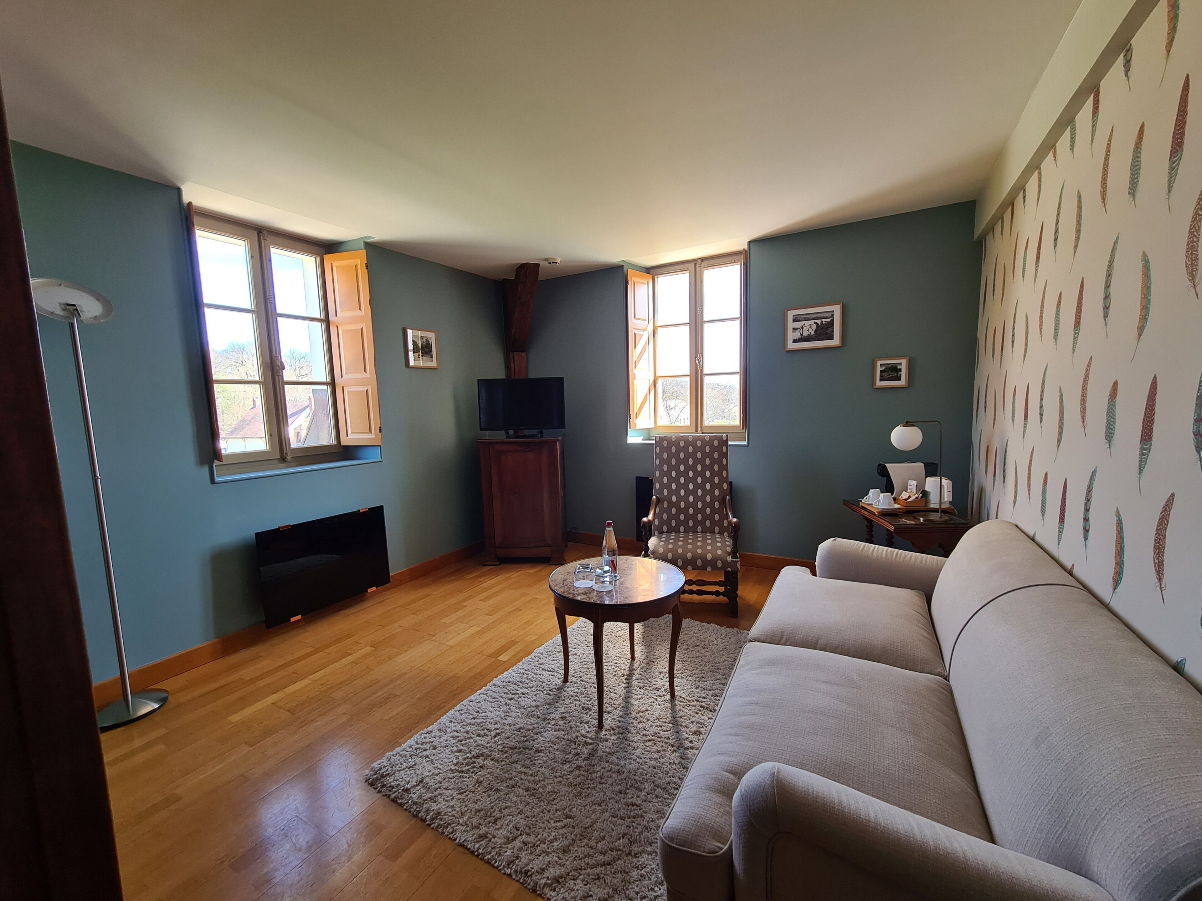 A living room with a sofa, a TV on a stand, a chair, a small table, and a fireplace.