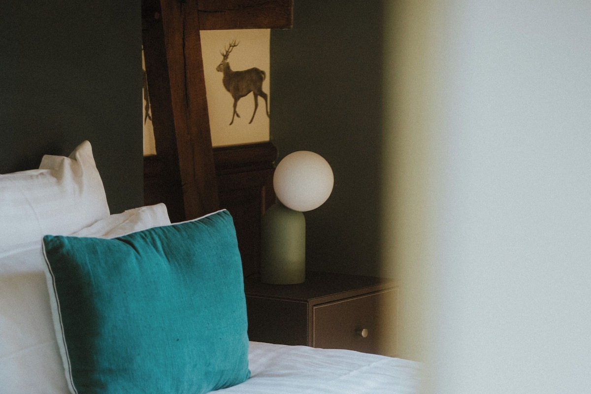 A bed with white and yellow bedding, teal and white pillows, and a wooden headboard.