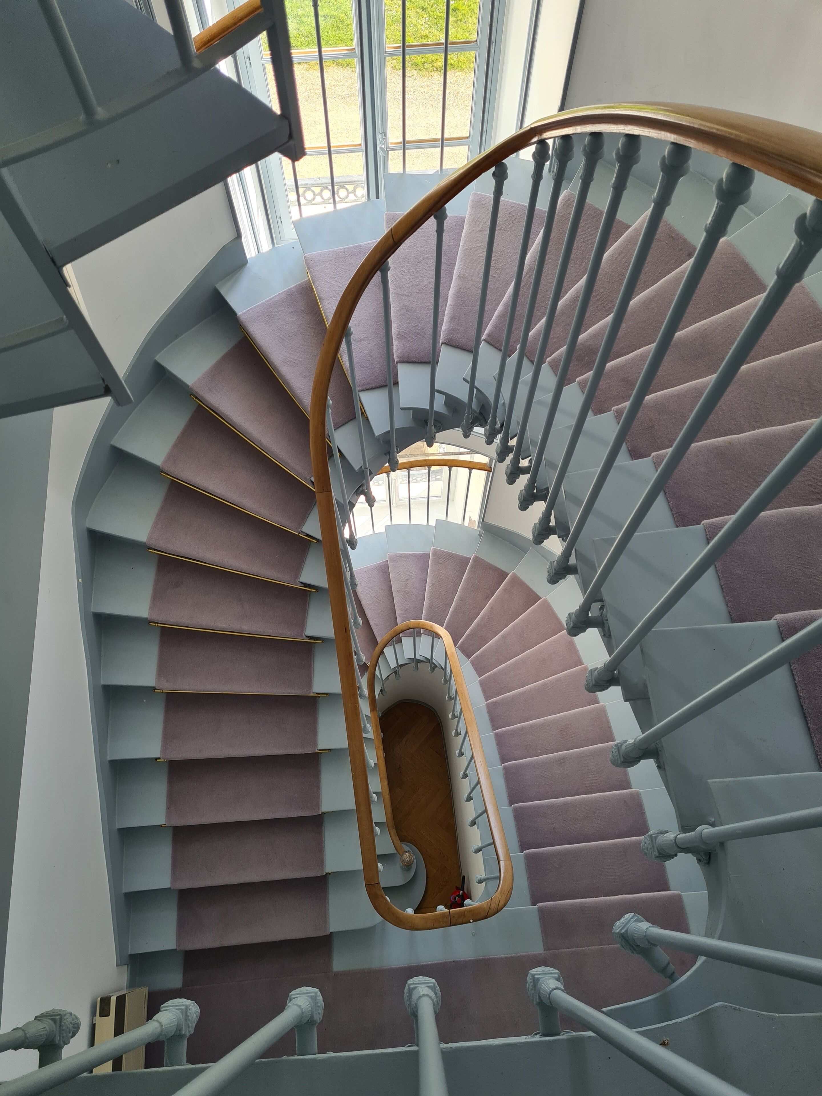 Una escalera de caracol con barandilla de madera y escalones grises.
