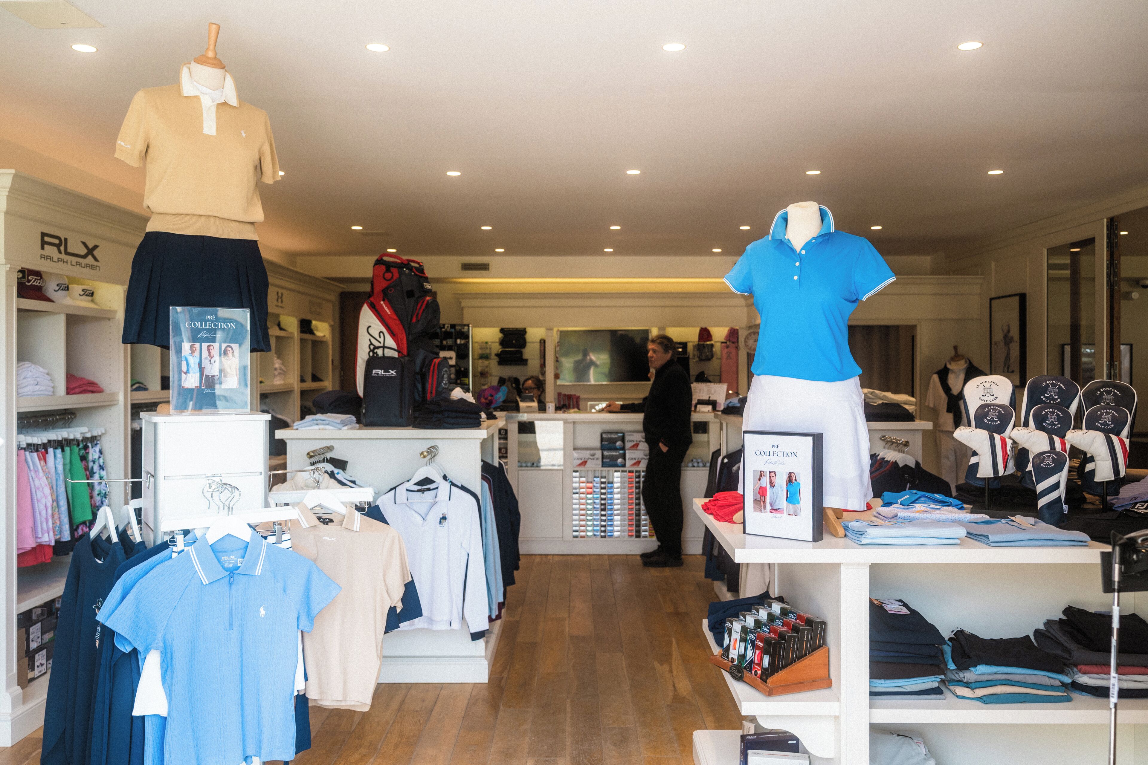 A clothing store with racks of shirts, a mannequin, and shelves with folded clothes.