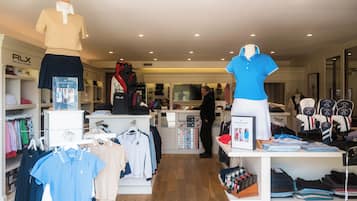 A clothing store with racks of shirts, a mannequin, and shelves with folded clothes.